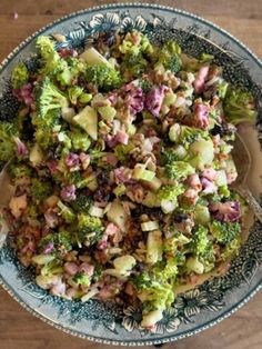 a bowl filled with broccoli salad on top of a wooden table