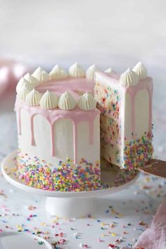 a white cake with pink frosting and sprinkles