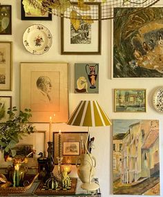 a room with many pictures on the wall and a lamp in front of it that is lit