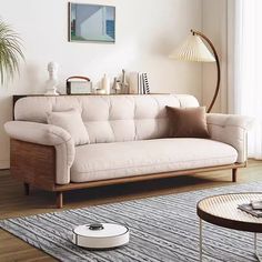 a living room with a couch, coffee table and lamp on the floor in front of a window