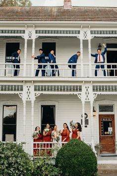 a group of people standing on the balcony of a white house