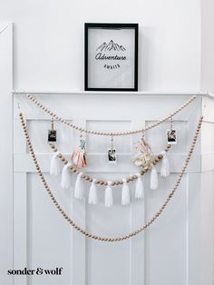 a white fireplace with some tassels hanging from it's mantle and a framed photo on the wall