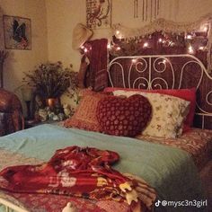 a bed with lots of pillows and blankets on it's headboard in a bedroom