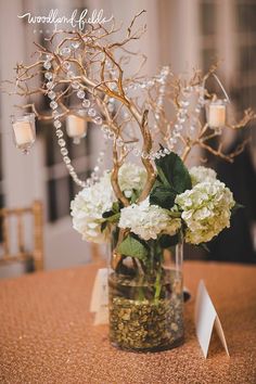 a vase filled with white flowers on top of a table next to a candle holder