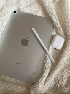 an apple ipad sitting on top of a white blanket next to a pen and mouse