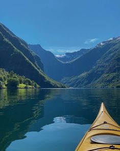 a kayak in the middle of a lake surrounded by mountains