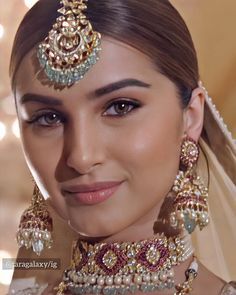 a beautiful woman in a bridal outfit with jewelry on her neck and headpiece