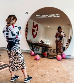 a woman standing in front of a mirror looking at her cell phone