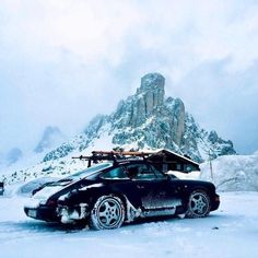 a car is parked in the snow near a mountain