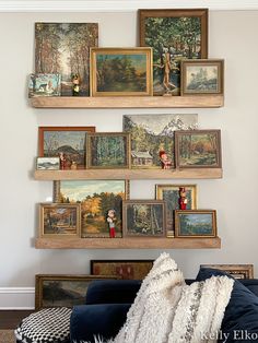 a living room filled with lots of framed pictures on the wall above a blue couch