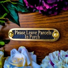 there is a plaque that says please leave parcells in porch next to some flowers