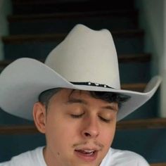 a young man wearing a white cowboy hat