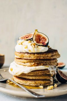 a stack of pancakes topped with whipped cream and figs