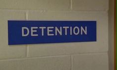 a blue and white sign that says detention on the side of a wall