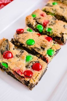 chocolate chip cookie bars with m & m candies on top are arranged on a white plate