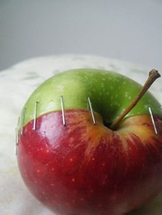 an apple with pins stuck in it sitting on a table