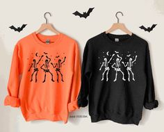 Listing: (1) Dancing Skeletons Sweatshirt  -Fun and cozy fleece crew to celebrate halloween and the spooky season!  Main Listing Photo: Orange sweatshirt with black design, and a black sweatshirt with white design.  Following Listing Photos... White and Ash Gray Sweatshirts both featuring black design.  Branding:  Adult: Gildan / Unisex sizing  *Size chart available in photos section  Looking for more halloween themed items? Check out all our halloween items here: https://www.etsy.com/shop/TCCTN Spooky Season Outfits, Black White Halloween, Photo Orange, Orange Sweatshirt, Holidays Ideas, Dancing Skeletons, White Halloween, Spooky Szn, Halloween Sweater