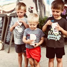 three young boys standing next to each other while holding cups and paper plates in their hands