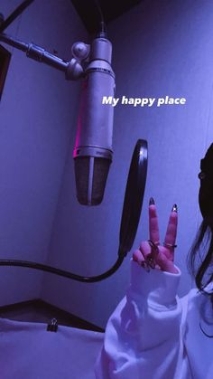 a woman holding up her peace sign in front of a microphone with the words my happy place written on it