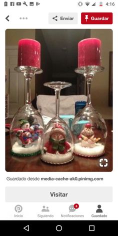 two wine glasses sitting on top of a table with christmas decorations in them and candles