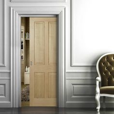 an empty room with a chair and bookcase on the floor, next to a white door