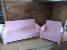 two pink couches sitting next to each other on top of a wooden table in a room