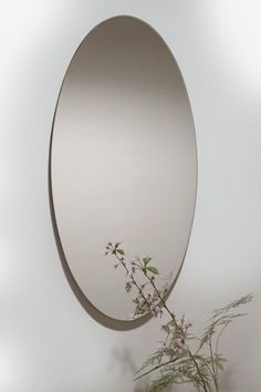 a round mirror hanging on the wall next to a plant