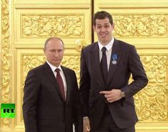 two men standing next to each other in front of flags and an ornate gold door