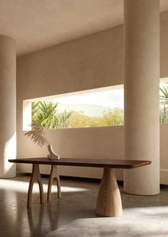 a wooden table sitting in the middle of a room next to two tall white pillars