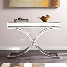 a glass table with a bowl on it and a painting in the corner behind it