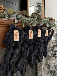 christmas stockings hanging from a mantel decorated with greenery