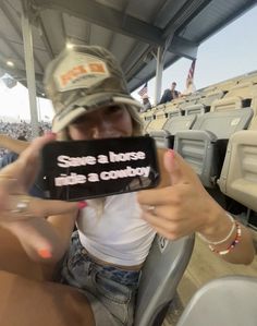 a woman sitting in a stadium holding up a cell phone