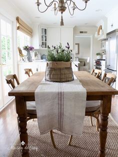 a wooden table topped with a basket filled with flowers next to a chandelier