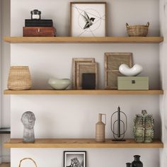 three wooden shelves with pictures, vases and other items on them in a living room