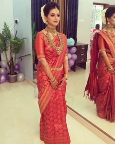 a woman in a red sari standing next to a mirror