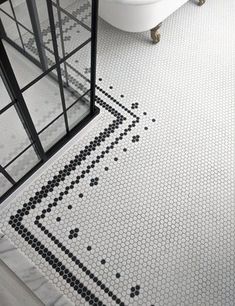 a bathroom with black and white tiles on the floor next to a bathtub, toilet and sink