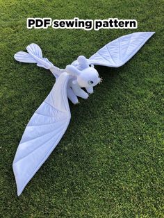 a white dragon sculpture laying on top of green grass in the middle of a field