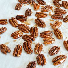 a bunch of pecans sitting on top of a piece of white paper with brown spots