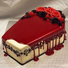 a cake with red and white frosting on the top, decorated with black roses