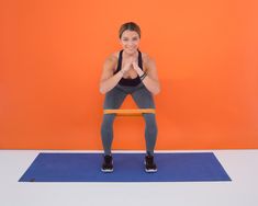 a woman standing on a blue mat with her hands together