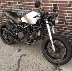 a black and white motorcycle parked next to a brick wall in front of a building