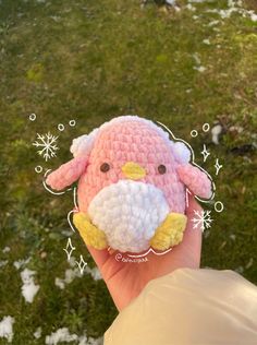 a hand holding a small crocheted animal in it's right hand and snowflakes on the ground