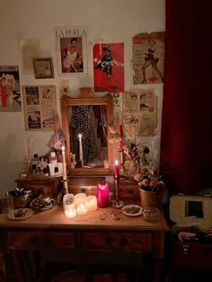 a vanity with candles and pictures on the wall above it, along with other items