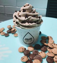 a cup filled with ice cream and cookies on top of a blue table covered in chocolate chips