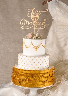 a white and gold wedding cake sitting on top of a table