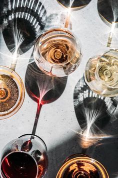 several glasses of wine sitting on top of a table next to each other with different wines in them