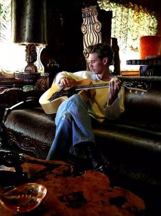 a man sitting on a couch holding a guitar