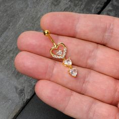 a person is holding an open heart shaped nose ring with two small hearts on it