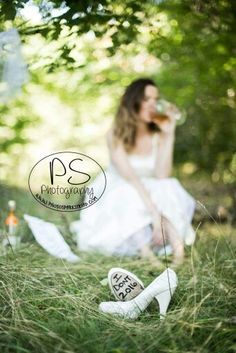 a woman sitting in the grass next to some shoes