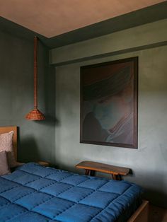 a bedroom with a bed and blue comforter next to a painting on the wall